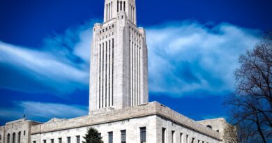 A tall white tower with a cloud in the background. The Lincoln State Capitol Building