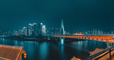 The Chongqing skyline, river and famous pointed bridge glow orange and blue in the night